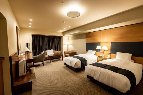 a hotel room with two beds and a couch at ホテルベルクラシック北見 in Kitami