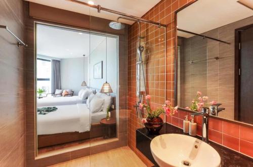 a bathroom with a large mirror and a bedroom at Khách Sạn Wins Apec Mũi Né in Mui Ne