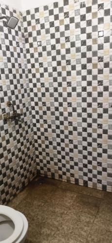 a bathroom with a toilet and a checkered wall at Madhav guest house in Agra