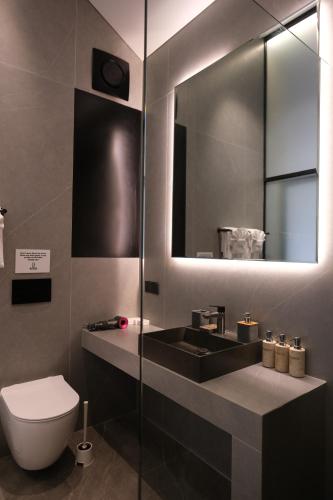 a bathroom with a sink and a toilet and a mirror at SWOI LOFT UMALAs Designer 2BR Private Pool Villa in Kerobokan