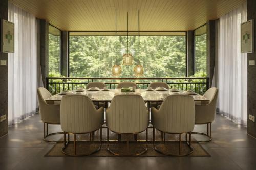 a dining room with a table and chairs and a large window at The Garden Villas in Ubud