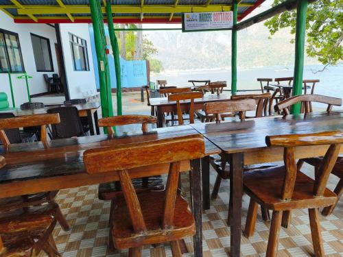 an empty restaurant with wooden tables and chairs at Hadefe Cottages Beach Front in El Nido