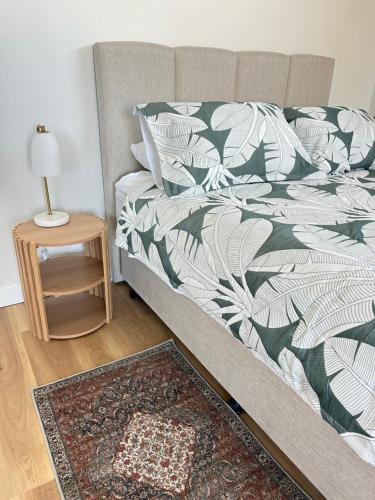a bed with a green and white blanket and a table at La Porta Rosa in Bunbury