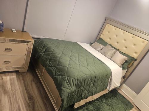 a small bedroom with a bed with a green comforter at Cozy & Roomy Apt close to all in Orchard Park