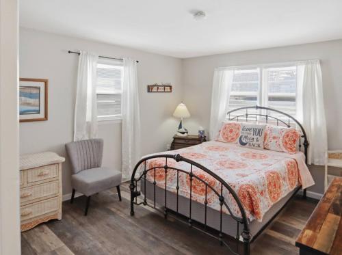 a bedroom with a bed and a chair and windows at Bay Front Manor House in Deale