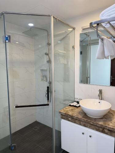 a bathroom with a glass shower and a sink at Mercy Hotel in Hanoi