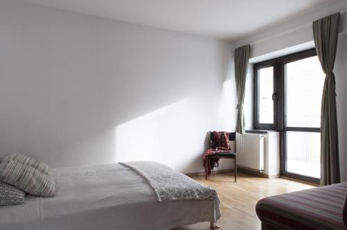 a white bedroom with a bed and a window at Apartament BB in Krynica Zdrój