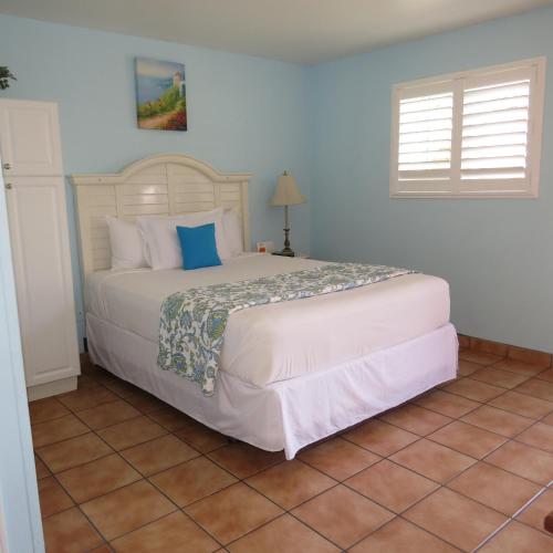 a bedroom with a large white bed with blue pillows at Leucadia Beach Inn in Encinitas