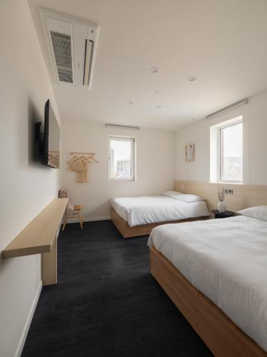 two beds in a room with white walls and windows at Unplug Anguk in Seoul