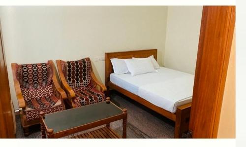 a small bedroom with a bed and two chairs at Celestial Homestay in Wayanad
