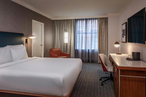 a hotel room with a bed and a desk at Courtyard by Marriott Boston Downtown in Boston
