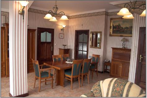 a dining room with a wooden table and chairs at Pensjonat Oleńka in Ustka