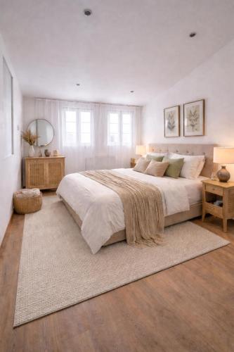 a large white bedroom with a large bed and a rug at Trianon Location in Bagnols-en-Forêt