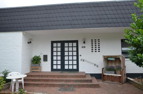 a white house with a black door and stairs at Seaside-Townhouse in Timmendorfer Strand