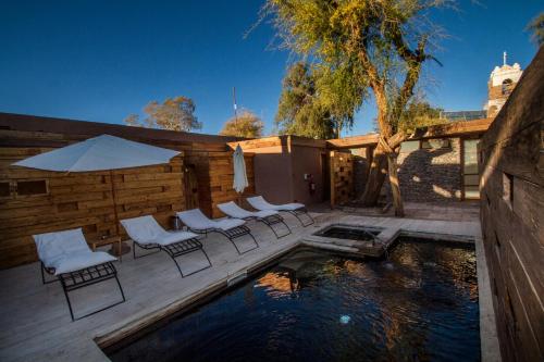 a row of wooden benches in front of a pool of water at Terrantai Lodge in San Pedro de Atacama