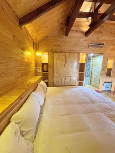 a large bed in a room with wooden walls at Homestay Gió Mộc !! in Làng Môn