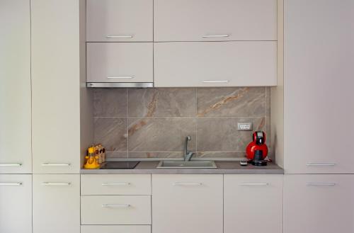a kitchen with white cabinets and a sink at Apartament Alezzi in Năvodari