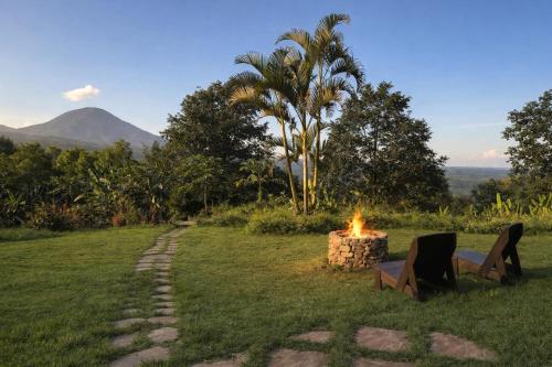 a fire pit in a field with a mountain in the background at Bali Barn Village in Munduk