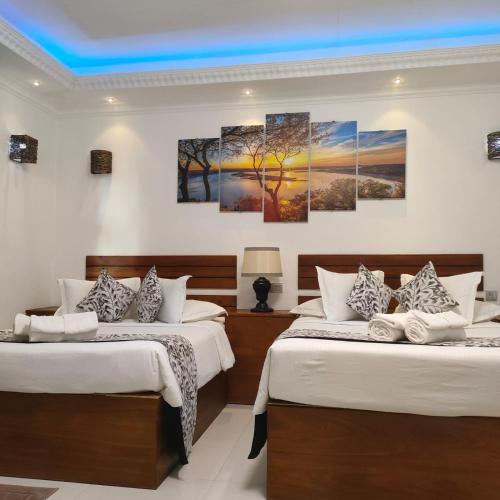 two beds in a room with three paintings on the wall at Blooming Holiday Resort in Anuradhapura