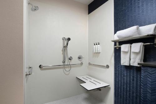 a bathroom with a shower with a toilet and towels at Fairfield Inn & Suites Dallas Park Central in Dallas