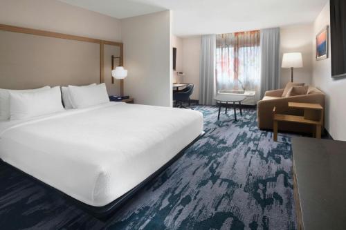 a hotel room with a large white bed and a chair at Fairfield Inn & Suites Dallas Park Central in Dallas