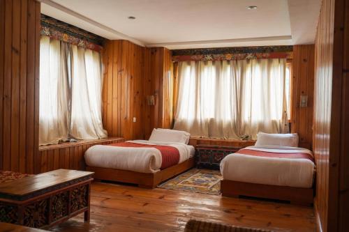 two beds in a room with wooden walls and windows at Samyae Resort in Jakar
