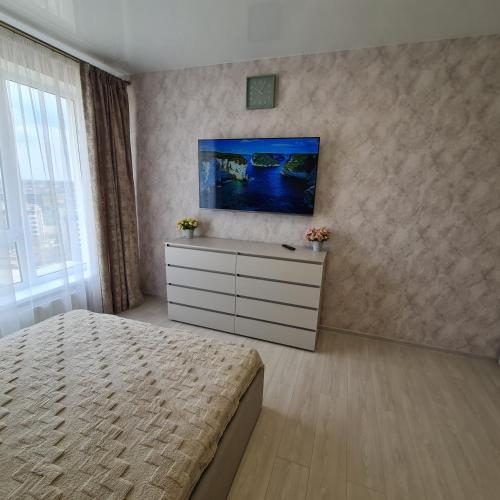 a bedroom with a bed and a dresser with a tv on the wall at Апартаменты in Odesa
