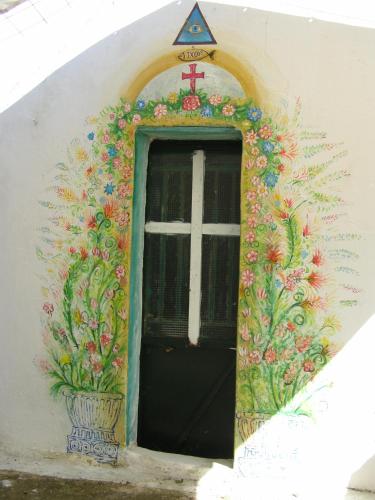 a door to a church with a cross and flowers at Kostas Walkers Point in Dafnáta
