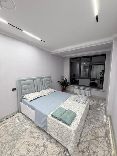 a bedroom with a bed and a chair and windows at Frunze Residence in Osh