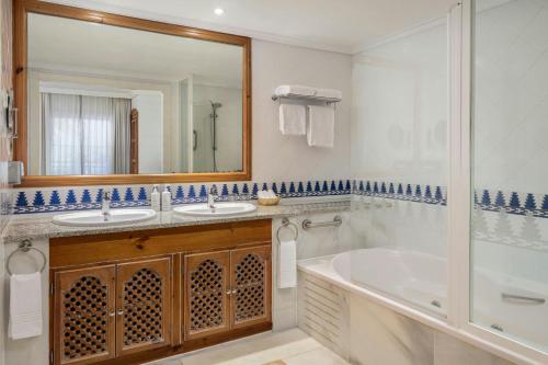 a bathroom with two sinks and a tub and a mirror at Marriott's Marbella Beach Resort in Marbella