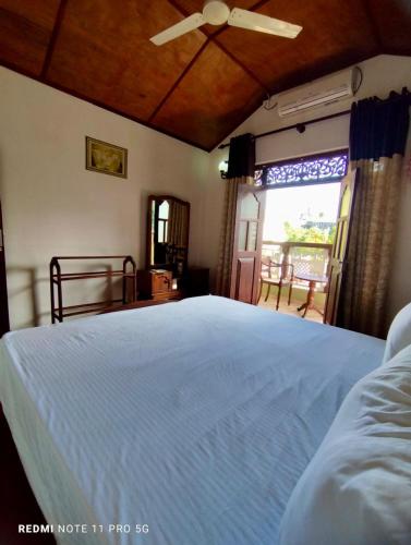 a bedroom with a white bed and a window at Sithula Villa in Bentota