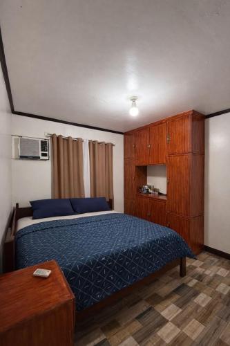 a bedroom with a blue bed and wooden cabinets at Tribo Zamani in General Luna