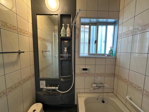 a bathroom with a tub and a sink and a mirror at Guesthouse Azumaya 2nd in Matsumoto