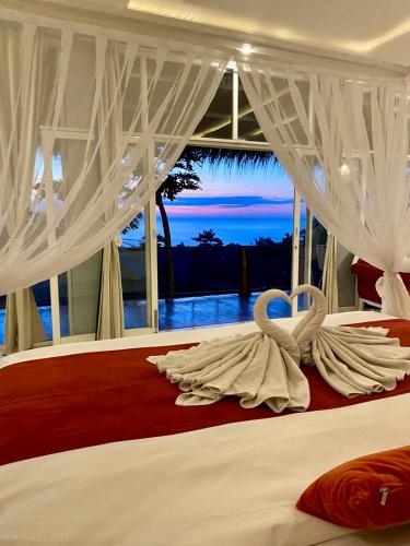 two swans sitting on a bed in a bedroom at Oceanview Cottage Cempaga - entire 2 BR Bungalow 135 sqm in Temukus