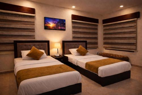 a hotel room with two beds and a tv at Panorama Amman Hotel in Amman
