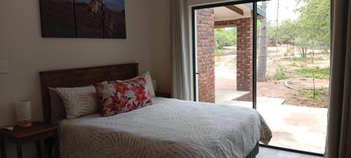 a bedroom with a bed and a sliding glass door at Vachellia View in Marloth Park
