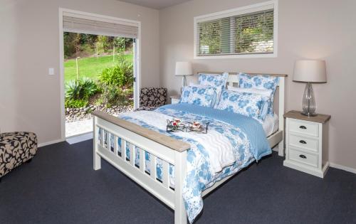 a bedroom with a bed with blue and white sheets and a window at Flaxmill Cove B&B in Whitianga