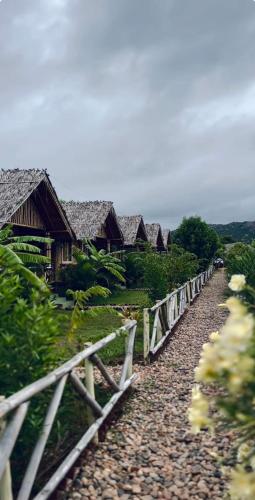a row of houses with a fence and a path at Mowgli's Cafe Hampi & Guest House in Hampi