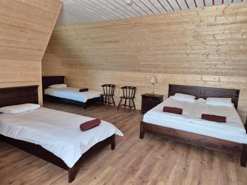 two beds in a room with wooden walls at Risti kodumajutus in Lemsi
