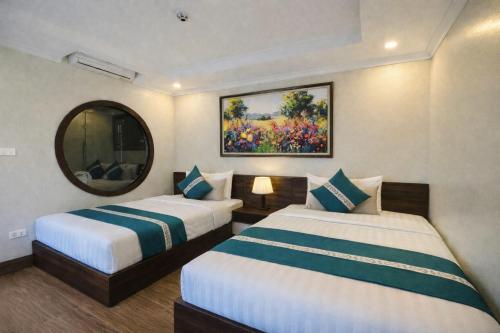 a hotel room with two beds and a mirror at Calla Lily Hotel in Sapa
