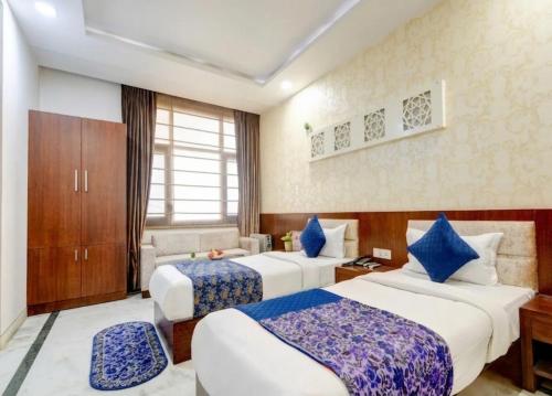 a hotel room with two beds and a couch at Monarch Residency Gurgaon in Gurgaon