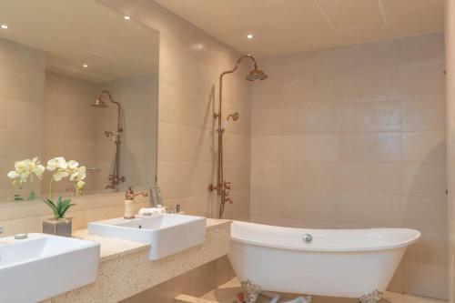 ein Badezimmer mit zwei Waschbecken und einer Badewanne in der Unterkunft The Monarch Hotel in Calasiao