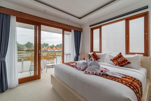 a bedroom with a large bed and a balcony at Cahya Restu Ubud Villa in Ubud