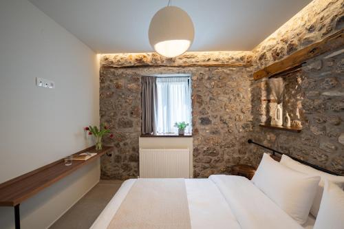 a bedroom with a stone wall with a bed and a window at The Alley in Litochoro