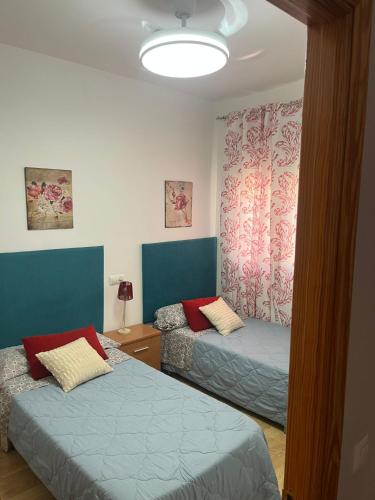 two beds in a room with blue and pink curtains at San Miguel in Membrilla