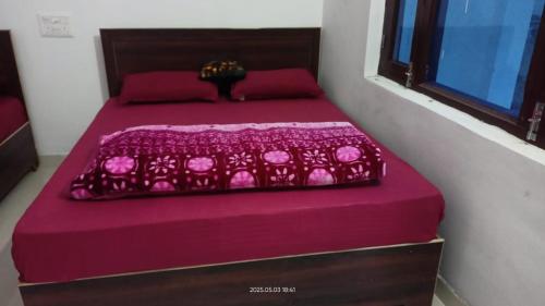 a bedroom with two beds with purple sheets and a window at Hotel Mahadev in Sonprayag