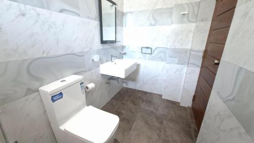 a white bathroom with a toilet and a sink at Haven Stay in Sri Jayewardenepura Kotte