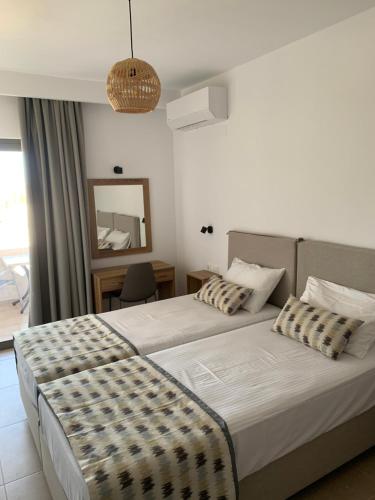 a hotel room with two beds and a mirror at Anemoni Studios in Plakias