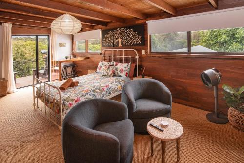 a bedroom with a bed and two chairs and a table at The Enchanted Stone Cottage in Margaret River Town