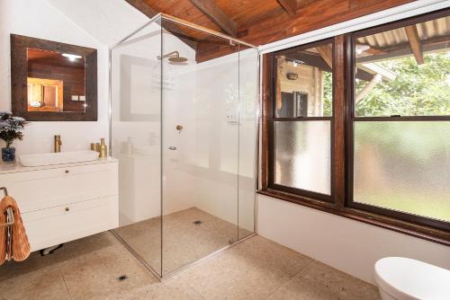 a bathroom with a glass shower and a sink at The Enchanted Stone Cottage in Margaret River Town
